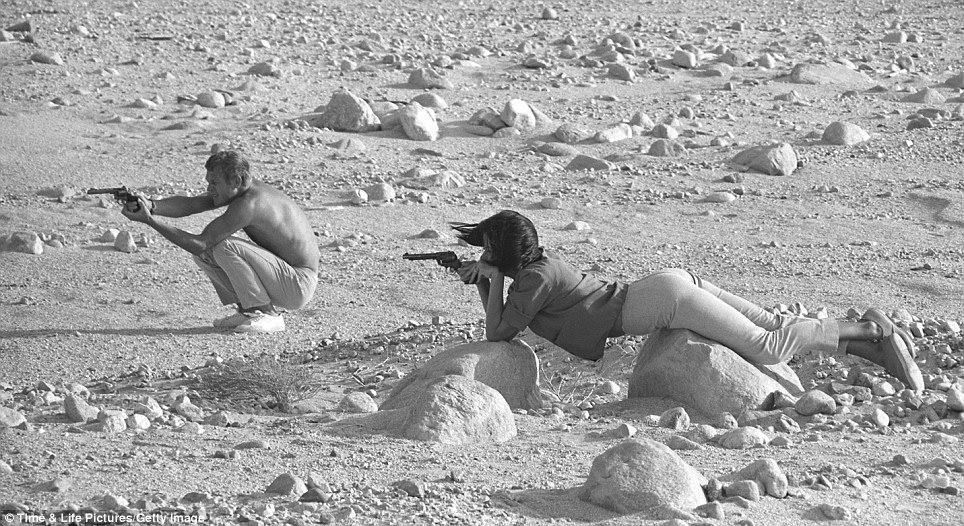 Steve McQueen and his wife, Neile Adams, firing pistols in the Palm Springs desert in 1963